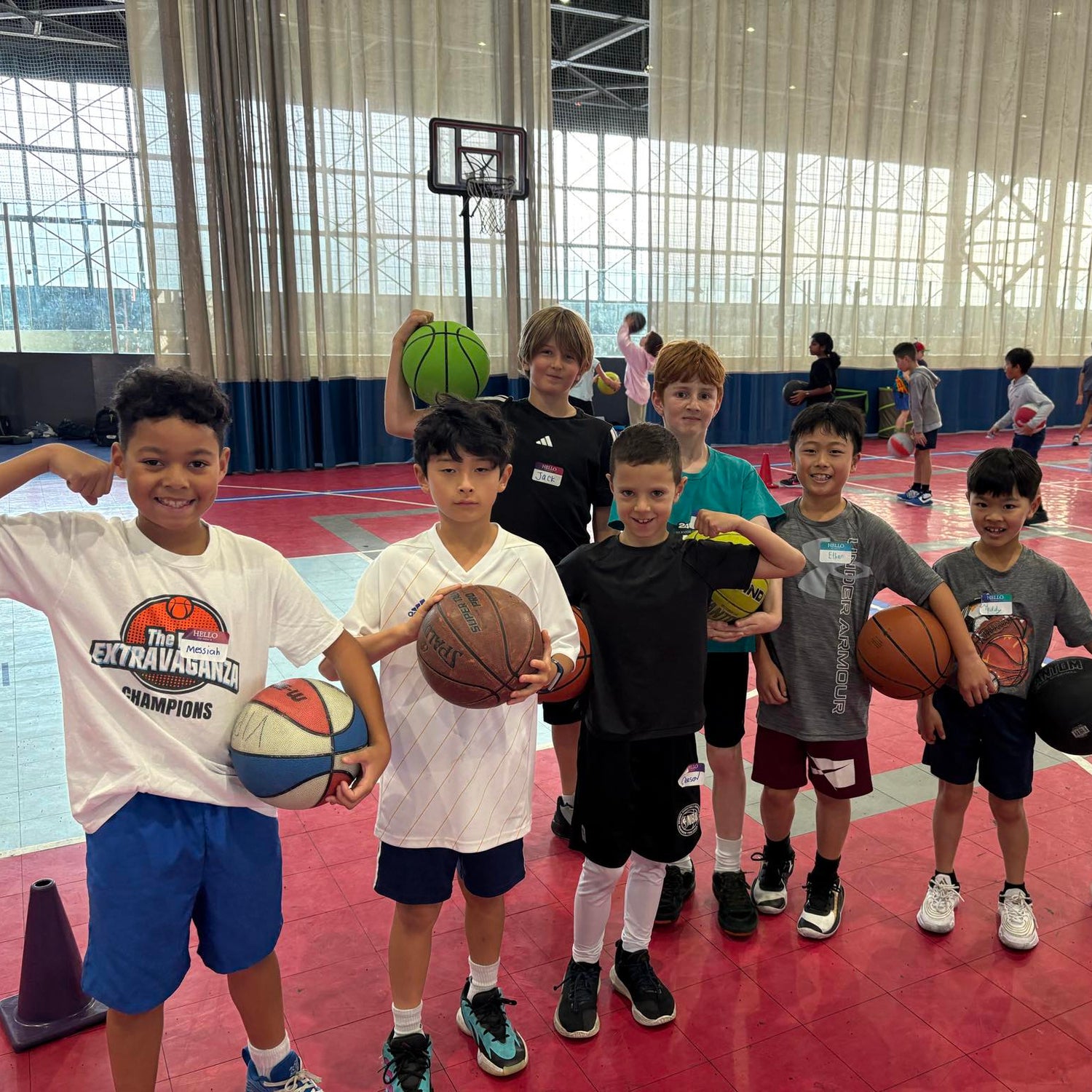 Max Skills Basketball Camp for Youth in Alameda, CA. Youth holding basketballs and flexing in an indoor gym in Alameda.